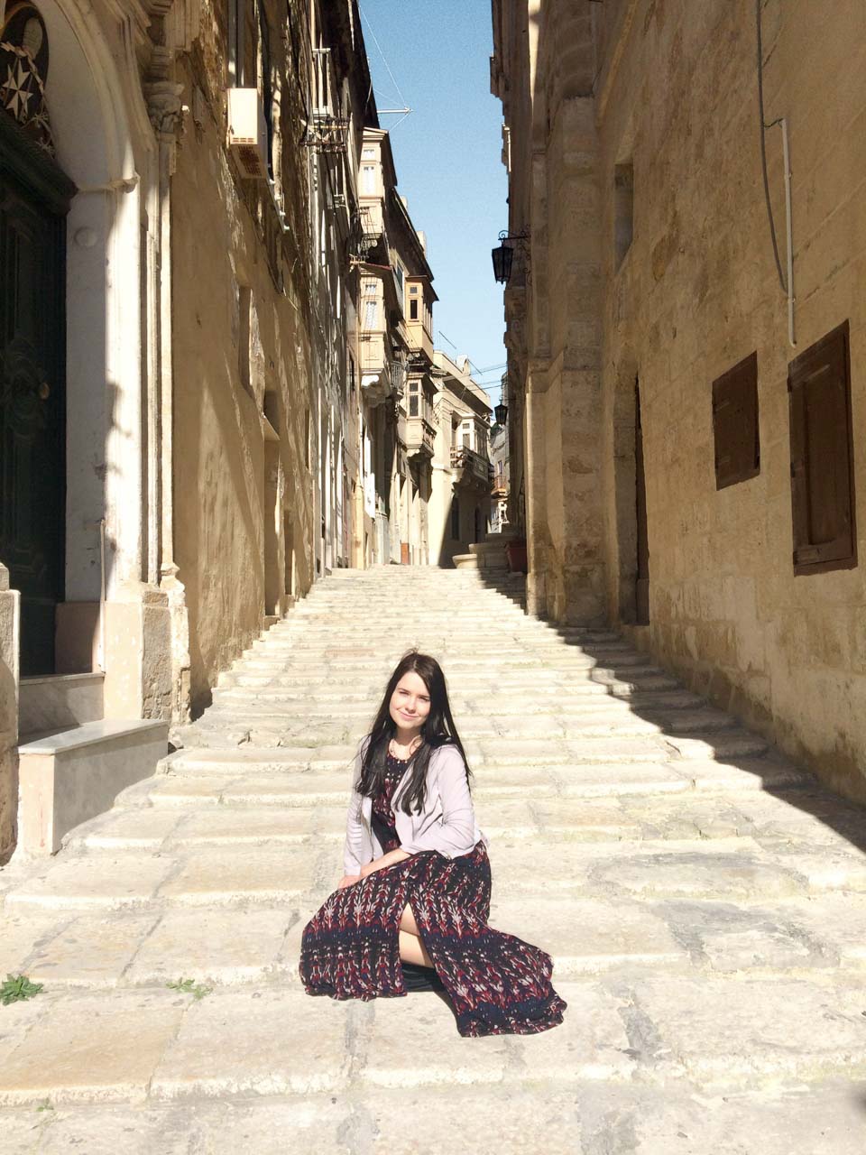 A girl sitting in a traditional street in Birgu, Malta