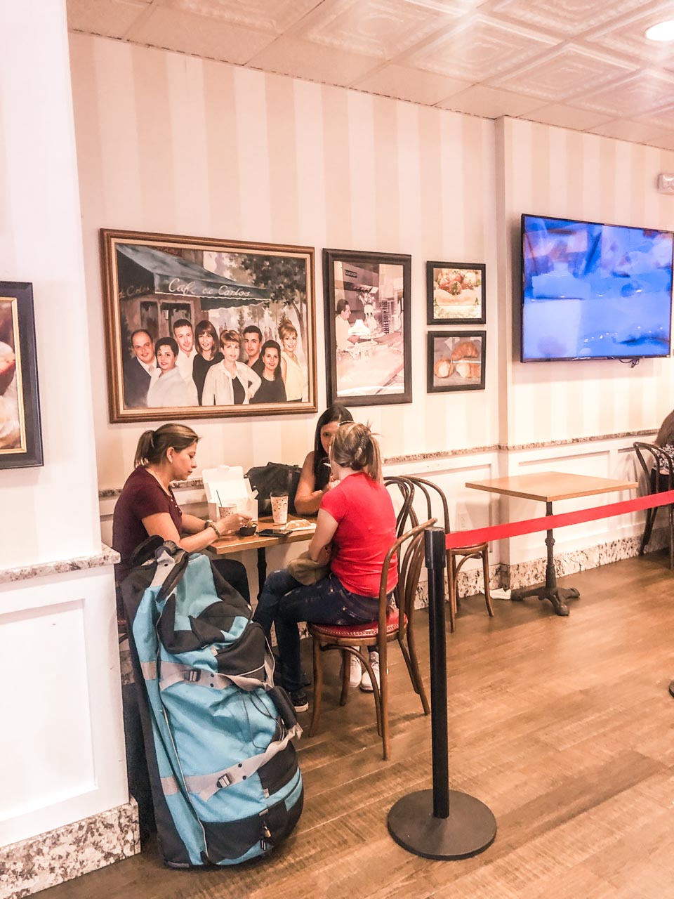 Women having cakes and coffee at Carlo's Bakery with framed Valastro family photos behind them