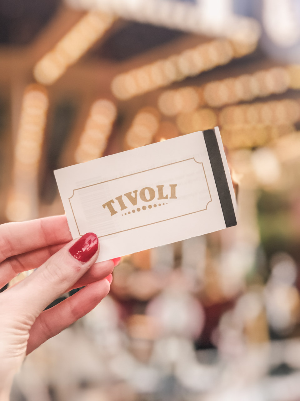 A girl holding an entrance ticket to Tivoli Gardens in Copenhagen, Denmark