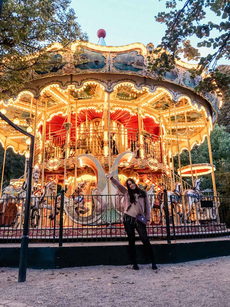 A girl posing in front of a carousel in Tivoli Gardens in Copenhagen, Denmark