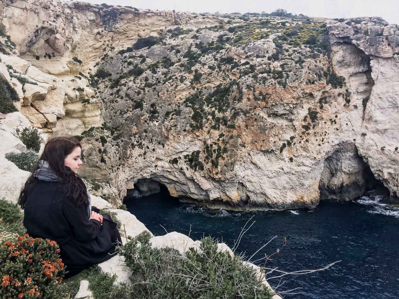 A girl sitting on the verge of the Blue Grotto, Malta