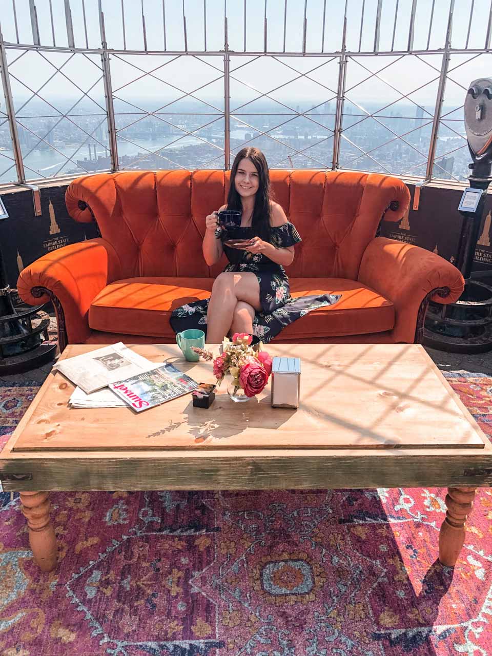 A girl sitting on the Friends sofa atop the Empire State Building in New York