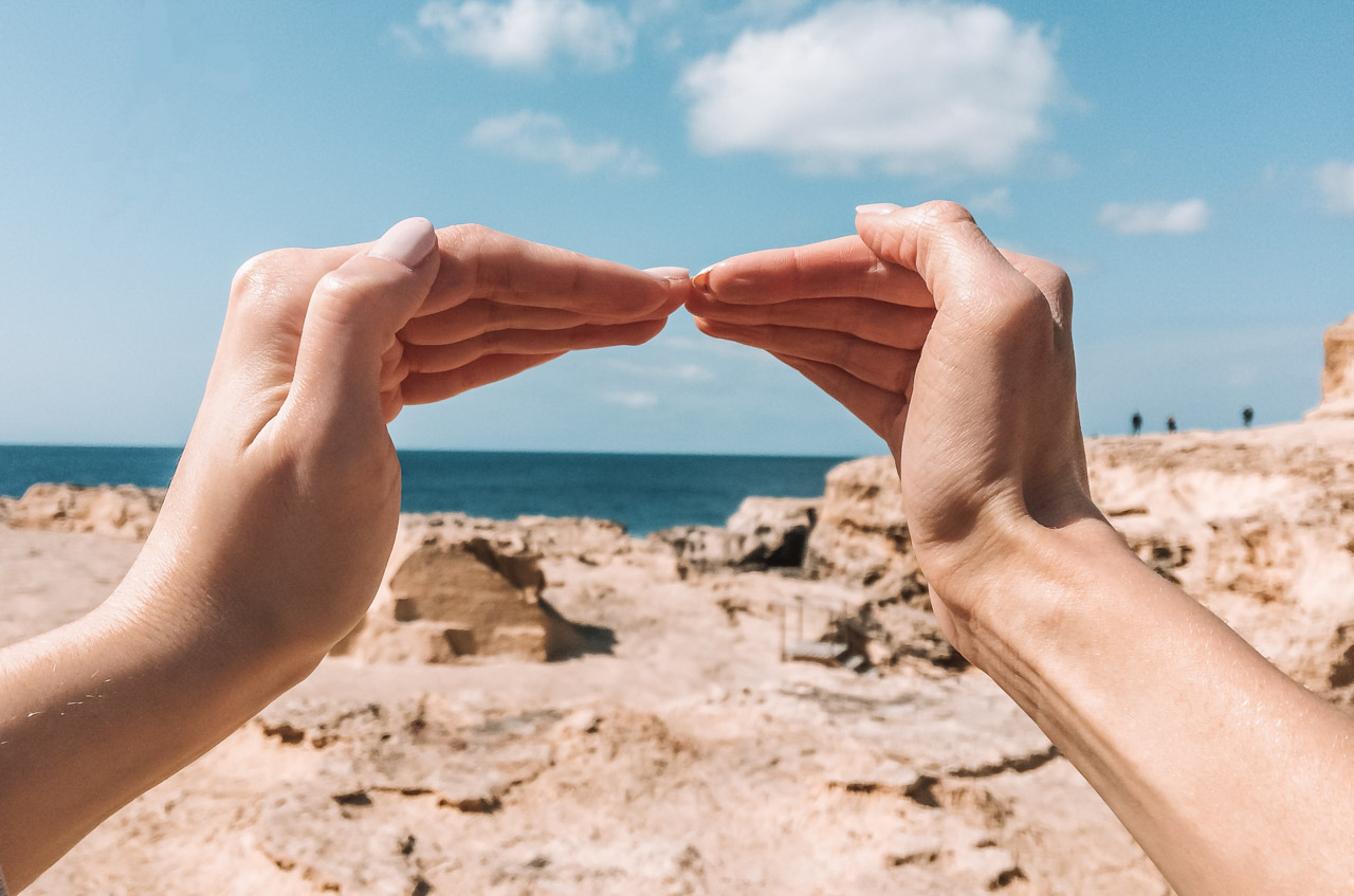 Two hands touching to recreate the shape of the Azure Window in Gozo