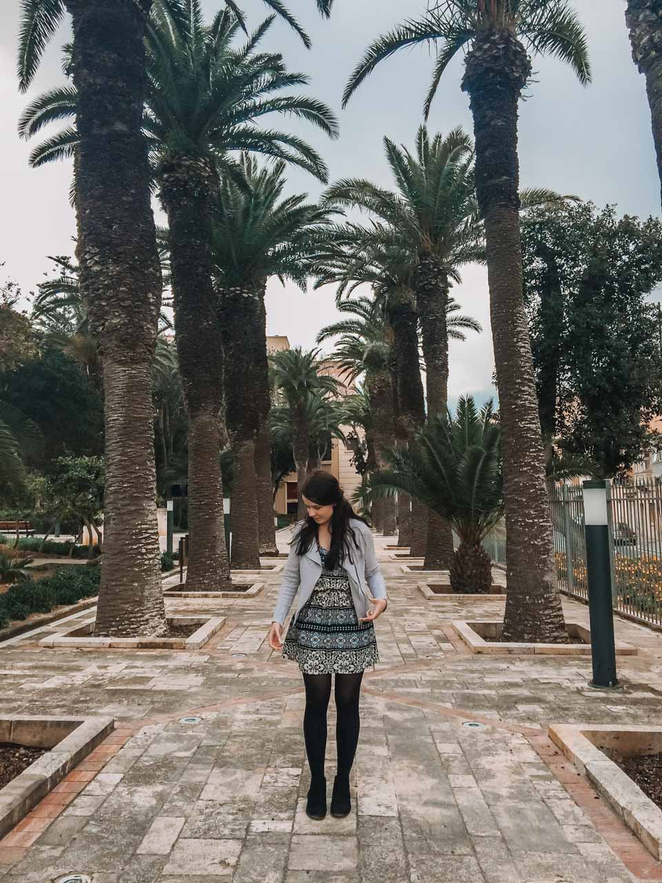 A girl in a patterned dress standing in the Villa Rundle Gardens in Gozo