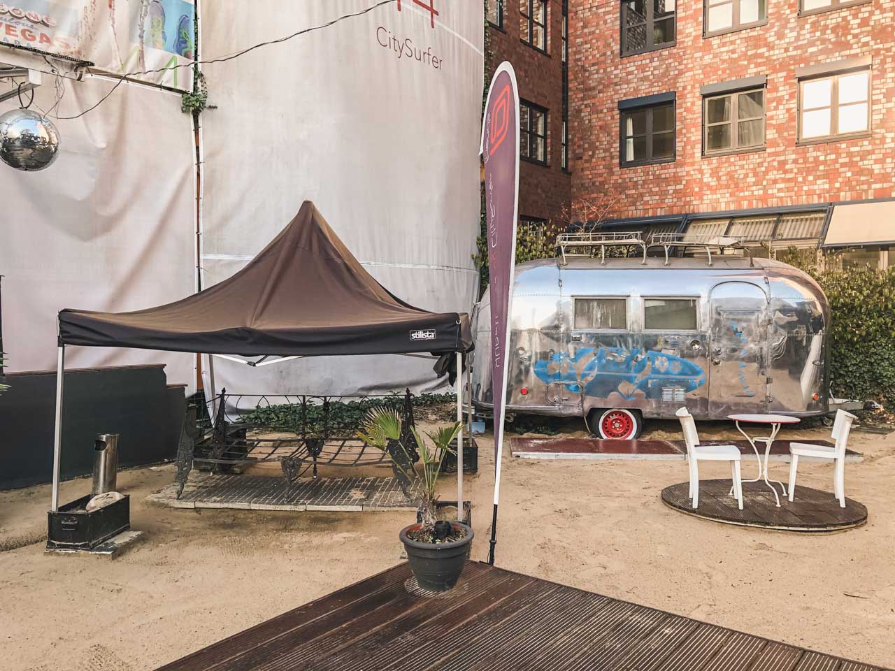 An outdoor terrace with an old camper van and a seating area