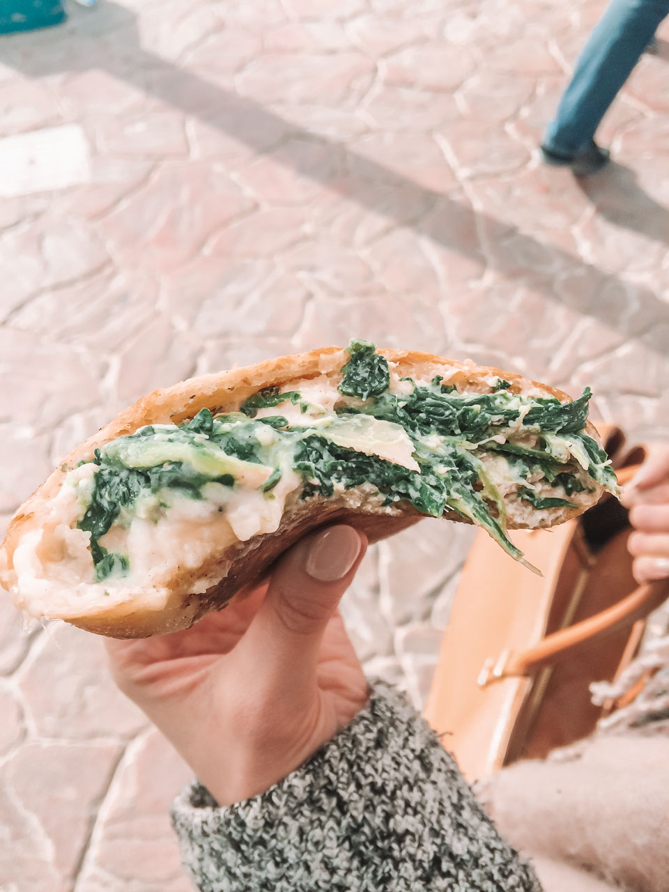 A girl holding a traditional Maltese pastry with spinach