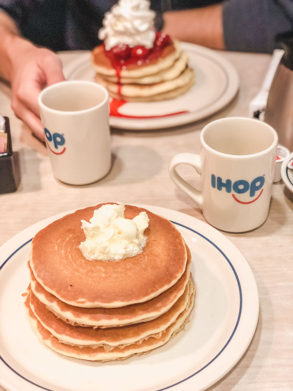 Two stacks of buttermilk and New York cheesecake pancakes and two cups of coffee on a table at IHOP