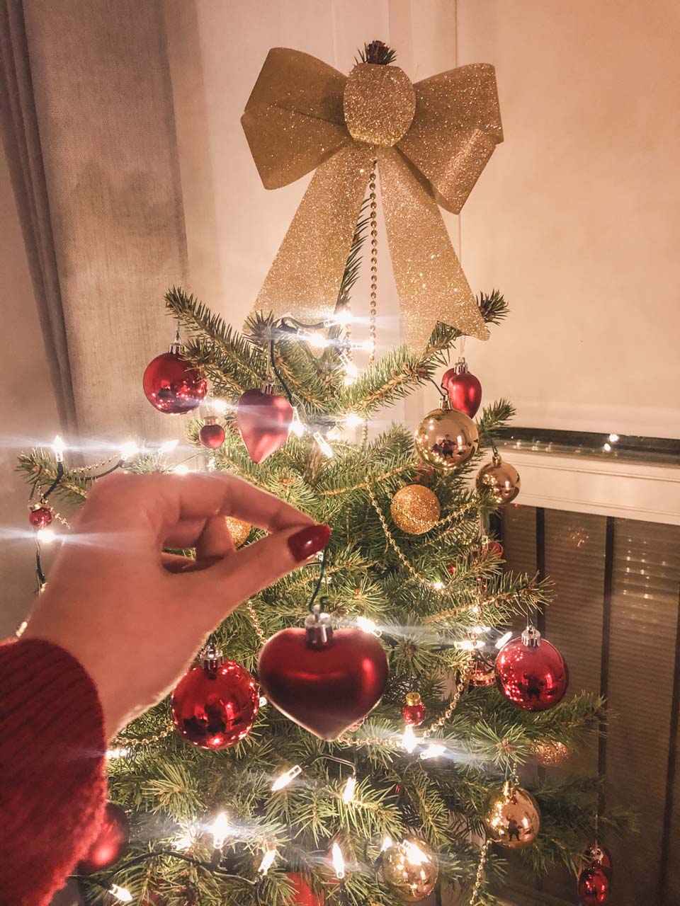 A girl hanging a heart-shaped ornament on a Christmas tree