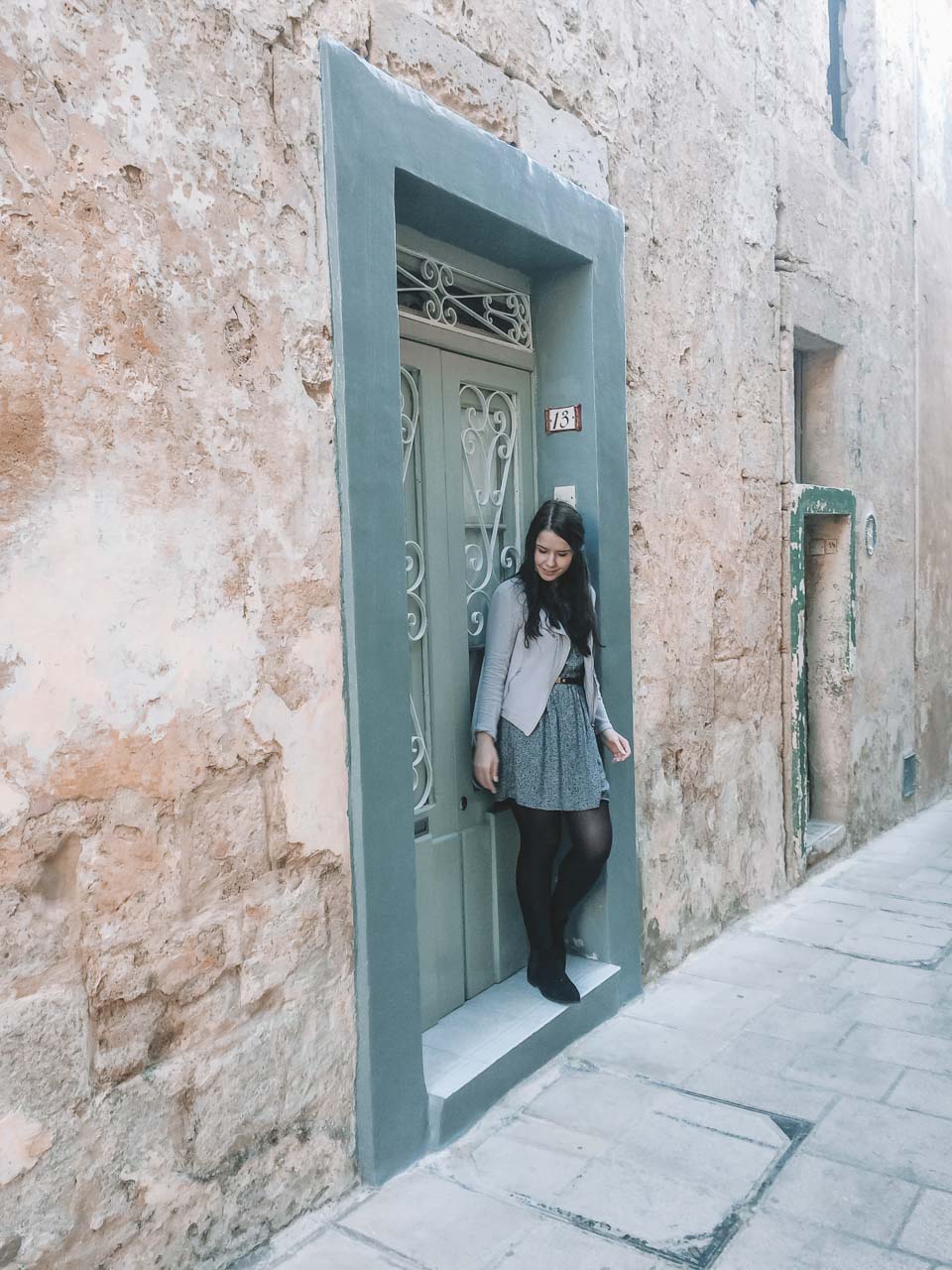 A girl standing in a doorway in a traditional alley in Mdina, Malta