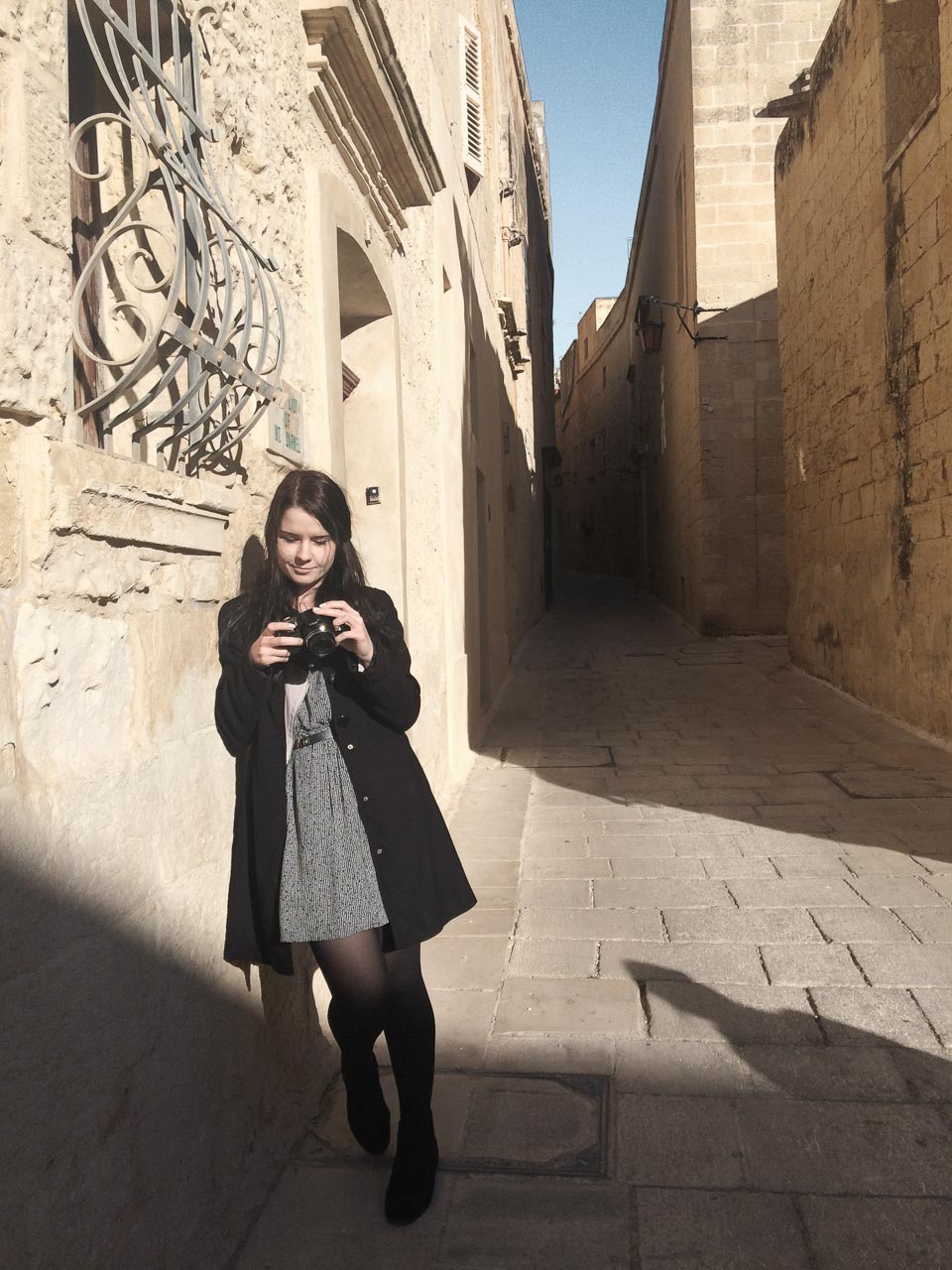 A girl with a camera standing in Mdina, Malta