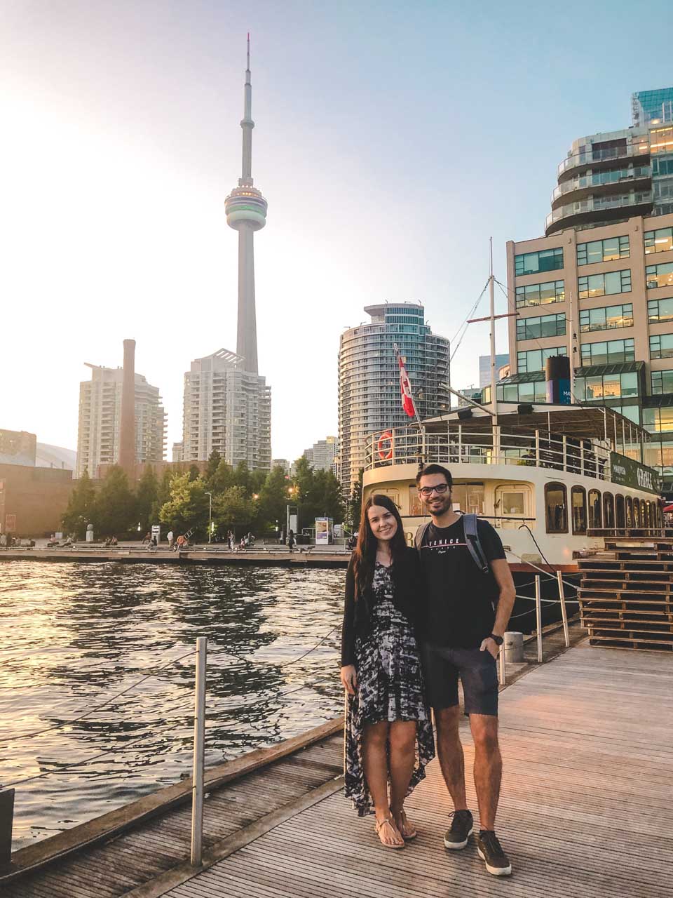 A couple standing in the Toronto harbour with the CN Tower in the background