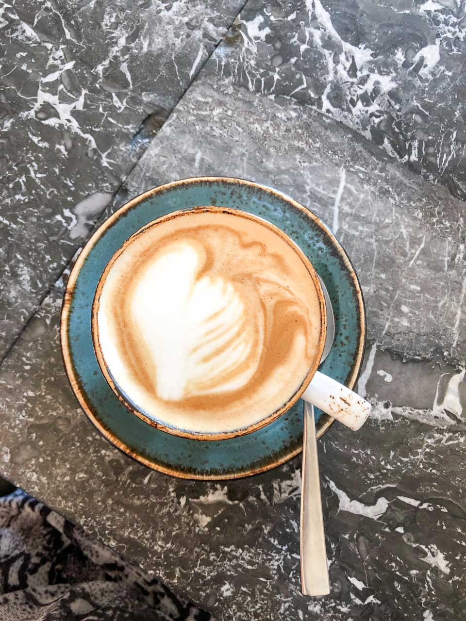A cup of cappuccino on a black marble table