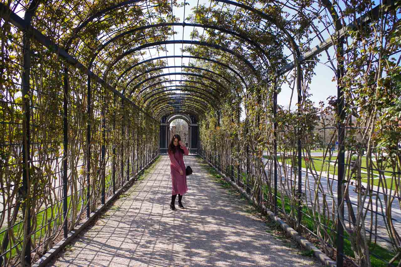 A girl standing under a pergola with vines in Schönbrunn Palace in Vienna, Austria