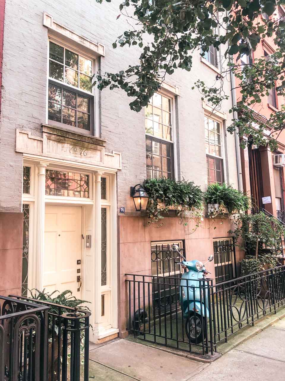 A pastel building in Manhattan with a blue scooter parked outside