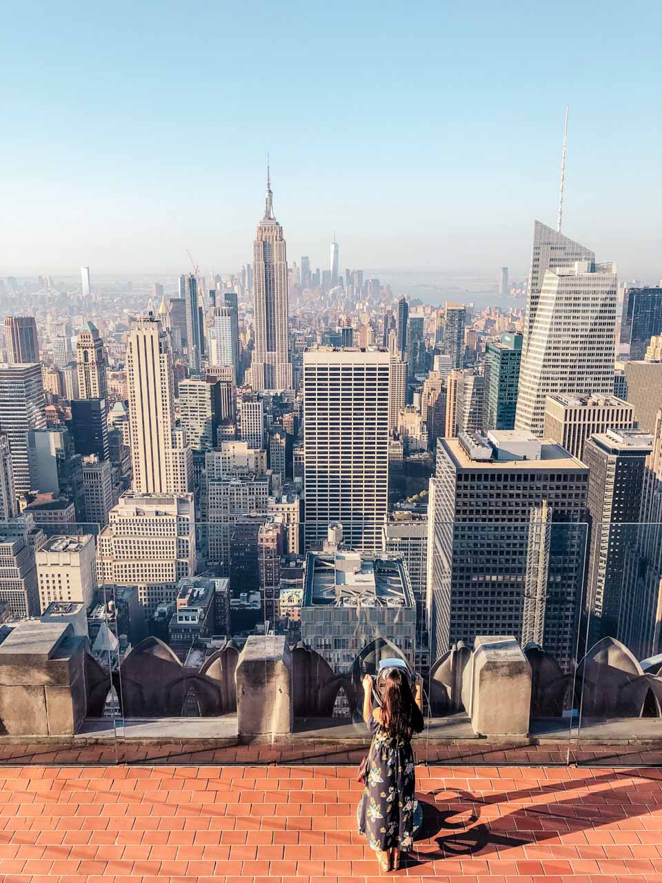 A bird's eye shot of a girl looking through the binoculars on Top of the Rock