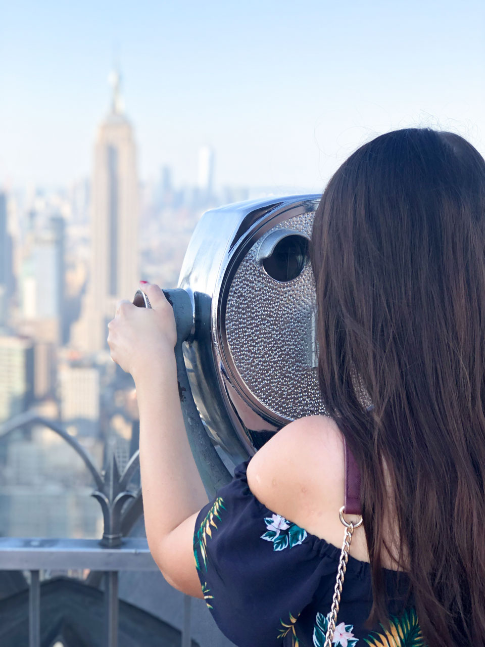 A girl looking through the binoculars on Top of the Rock