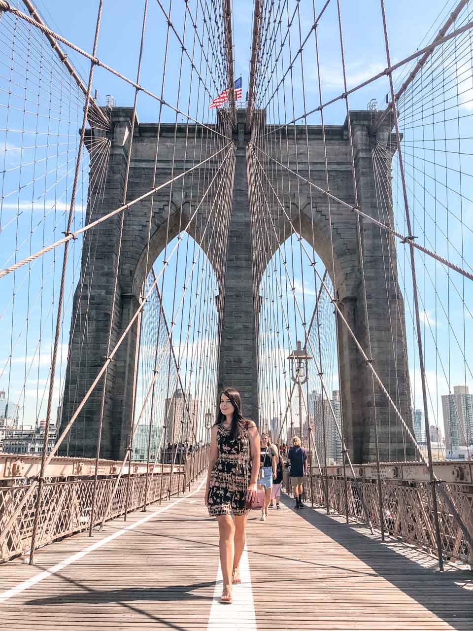 A girl in a dress walking across the Brooklyn Bridge