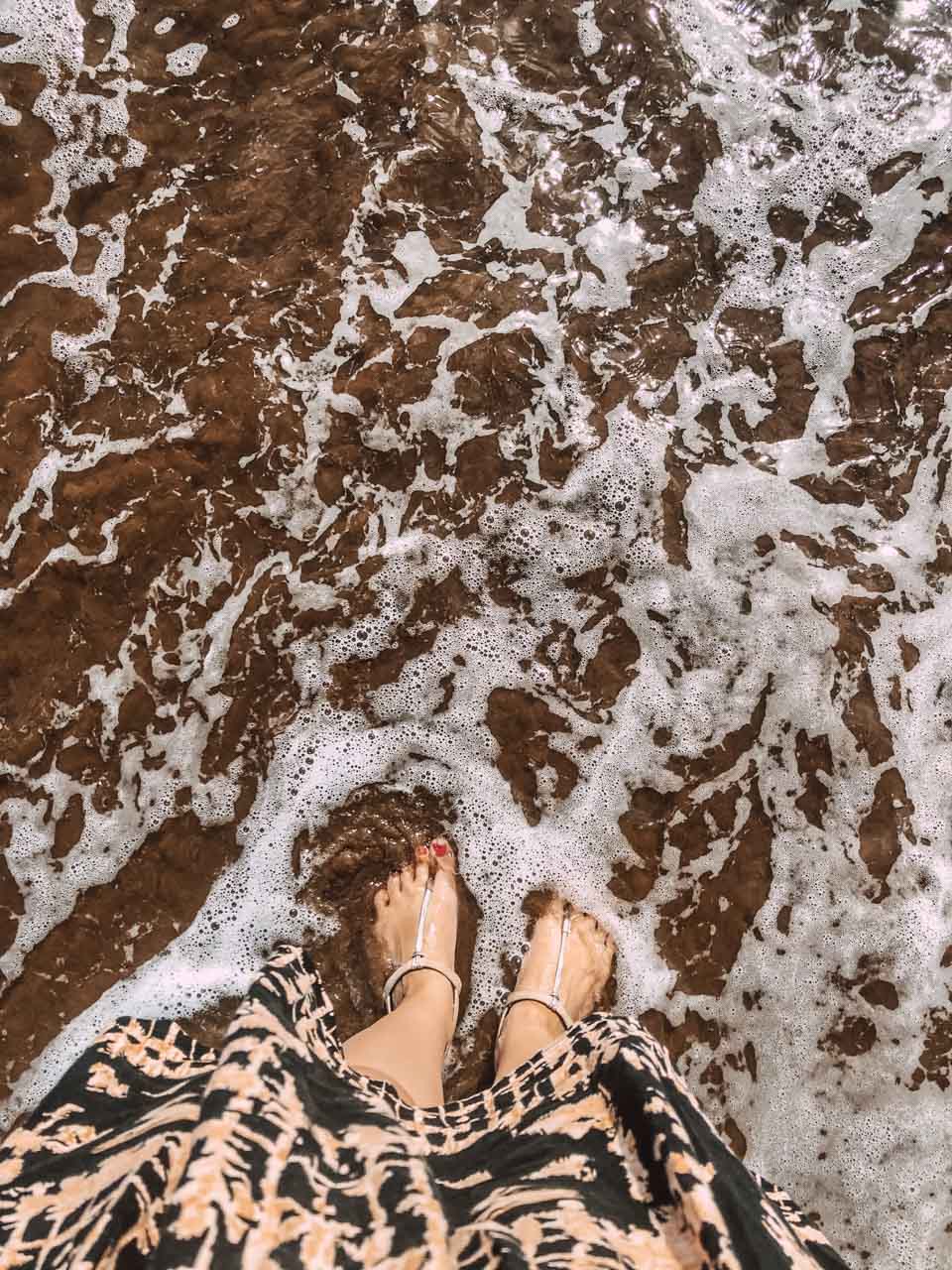 A bird's eye shot of a girl dipping her toes in the ocean