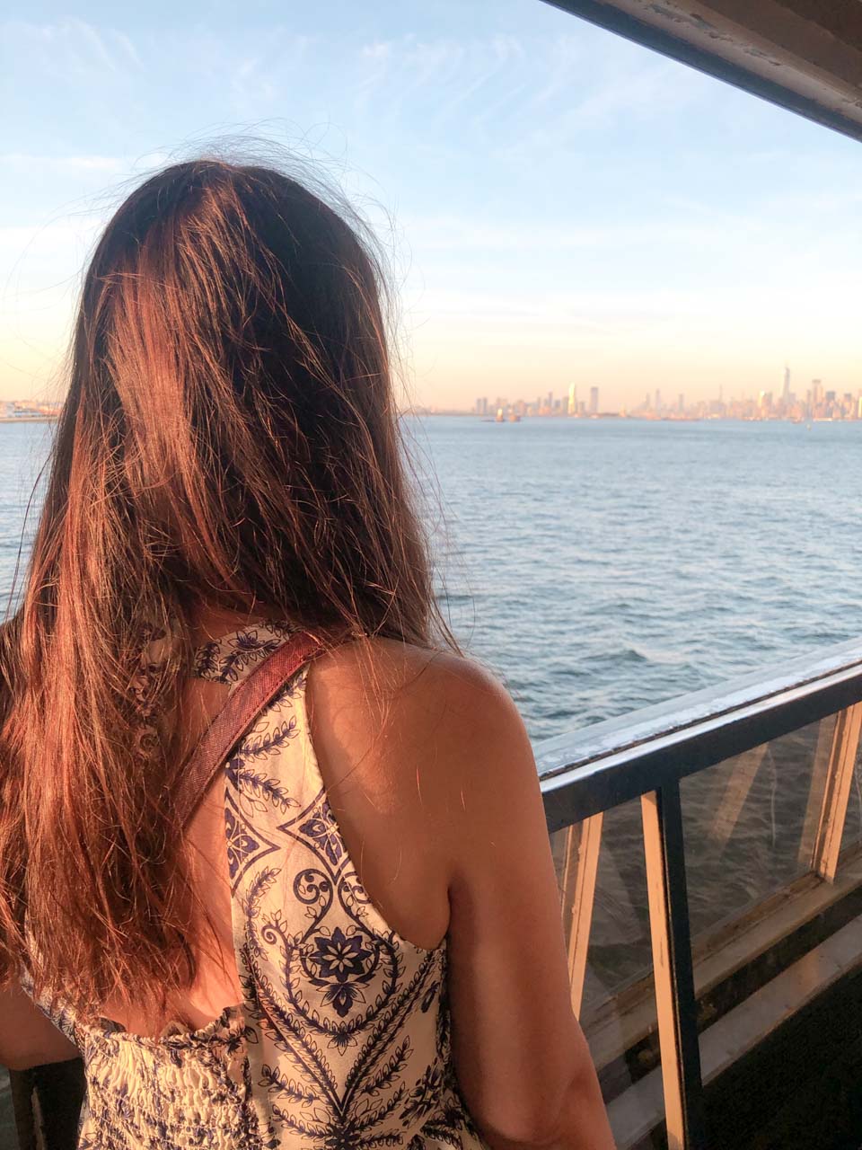 Girl with her back turned to the camera watching the Manhattan skyline from the Staten Island ferry