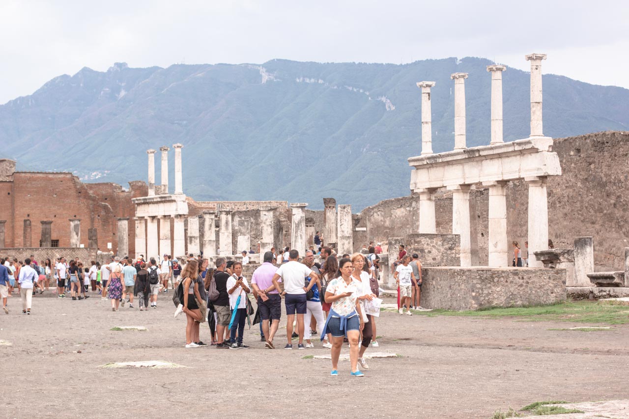 Tourists walking and looking at ruins inside Pompeii, Italy