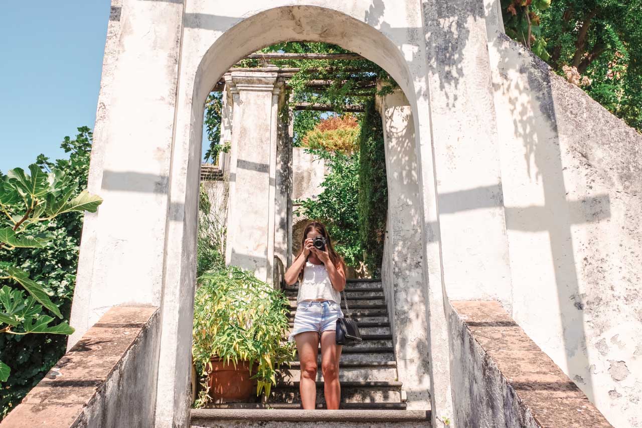 A girl pointing her camera at the photographer on the steps of Giardino della Minerva in Salerno