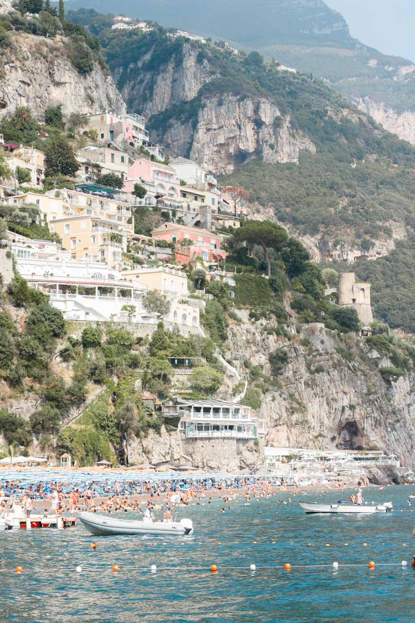 Boats on the sea in Positano with hillside houses in the background