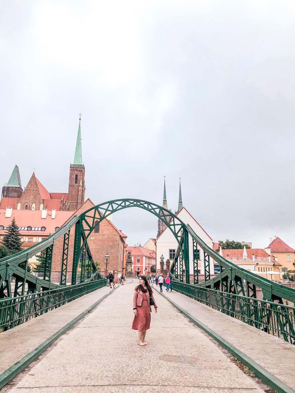 A woman in a pink dress standing on the Tumski Bridge in Wrocław