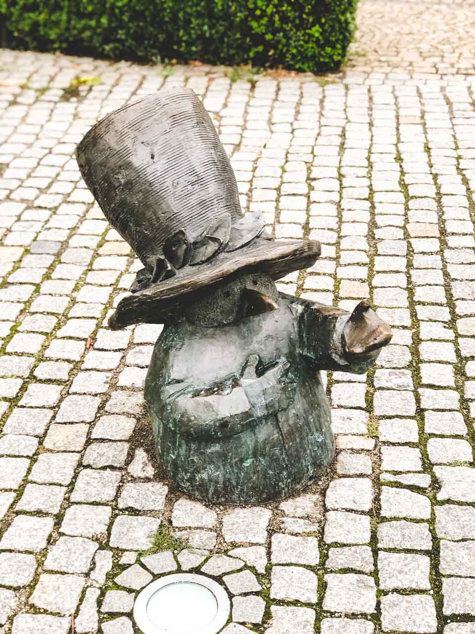 A figurine of a dwarf in a hat pointing at something outside the Wrocław Puppet Theatre