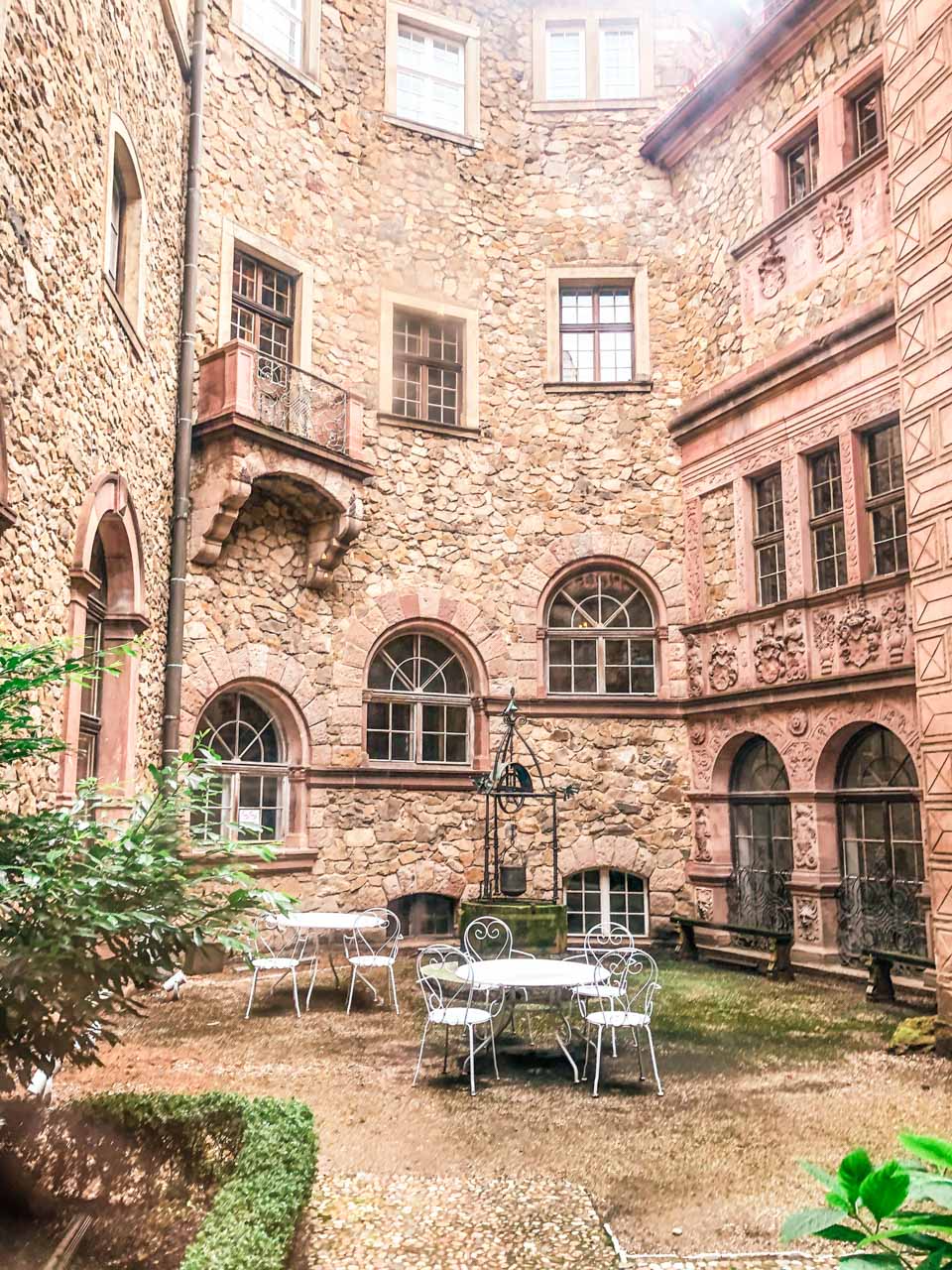 Two white tables with chairs inside an inner courtyard at Książ Castle