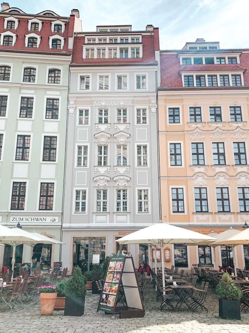 Pastel tenement houses with beer gardens outside on An der Frauenkirche in Dresden, Germany