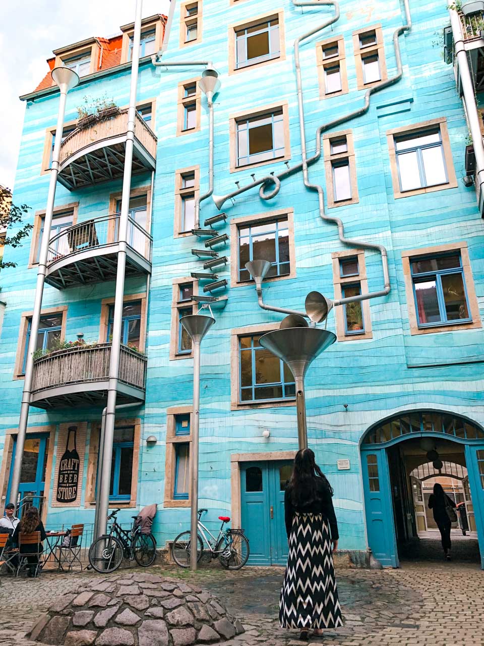 Woman in a black and white dress staring at the singing drain pipes in Kunsthofpassage in Dresden
