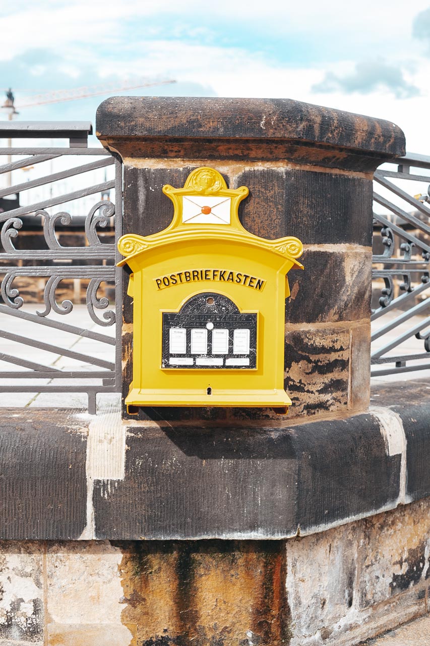 An old vintage yellow mailbox (Postbriefkasten) attached to the Augustus Bridge in Dresden, Germany