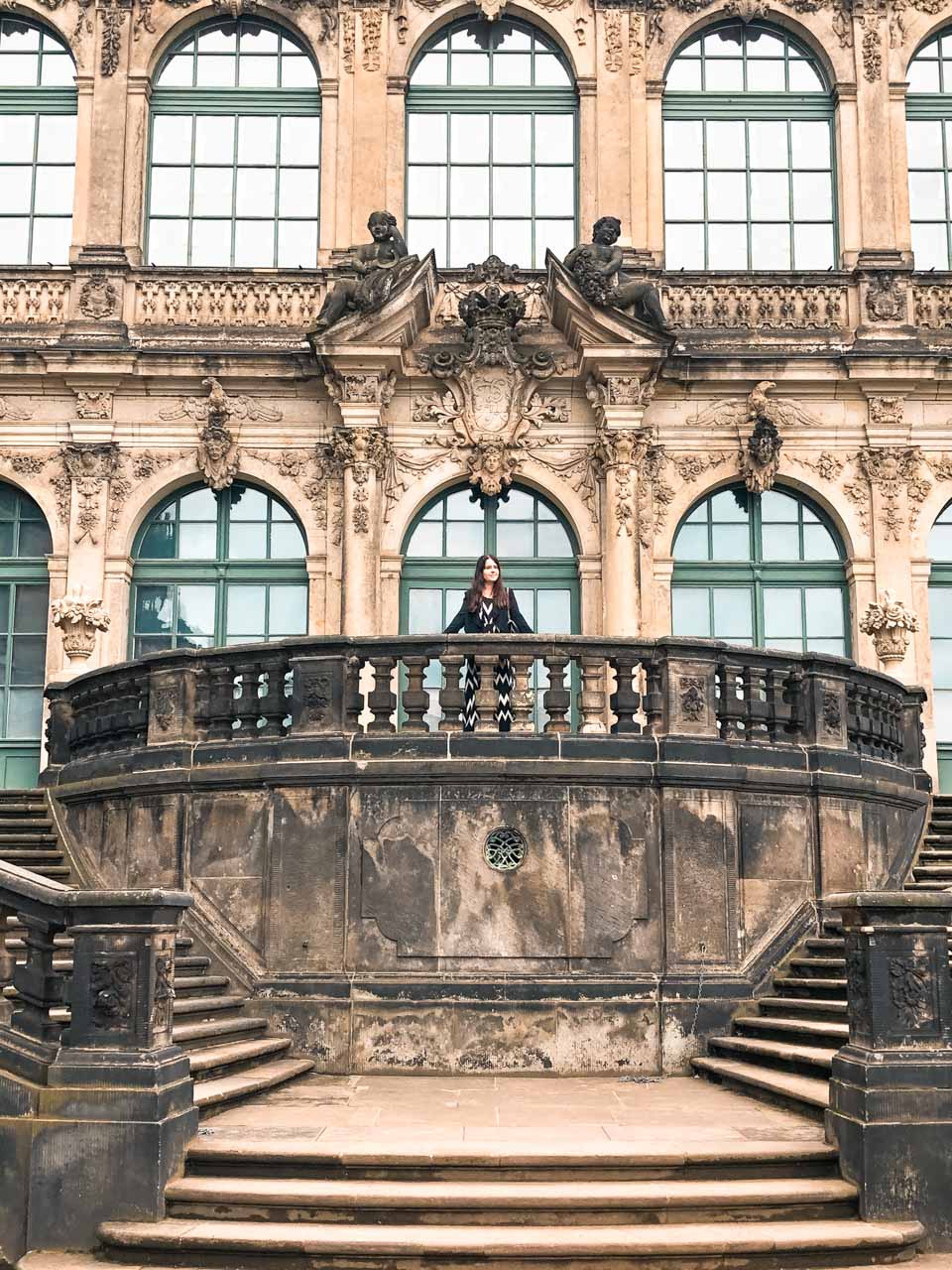 A woman in a black and white maxi dress leaning against a balustrade at Zwinger Palace