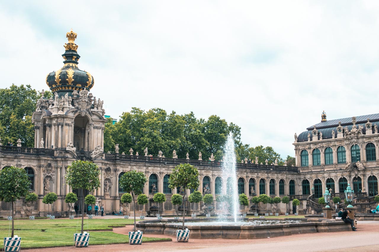 A fountain on Zwinger Square in Dresden, Germany with the Zwinger Crown Gate in the background