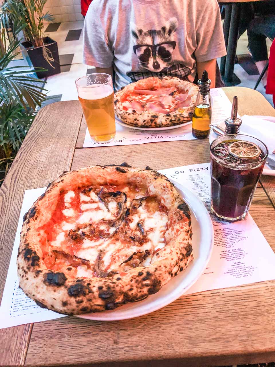 Two pizzas, a glass of beer and a glass of wine with Coke on a table at Iggy Pizza