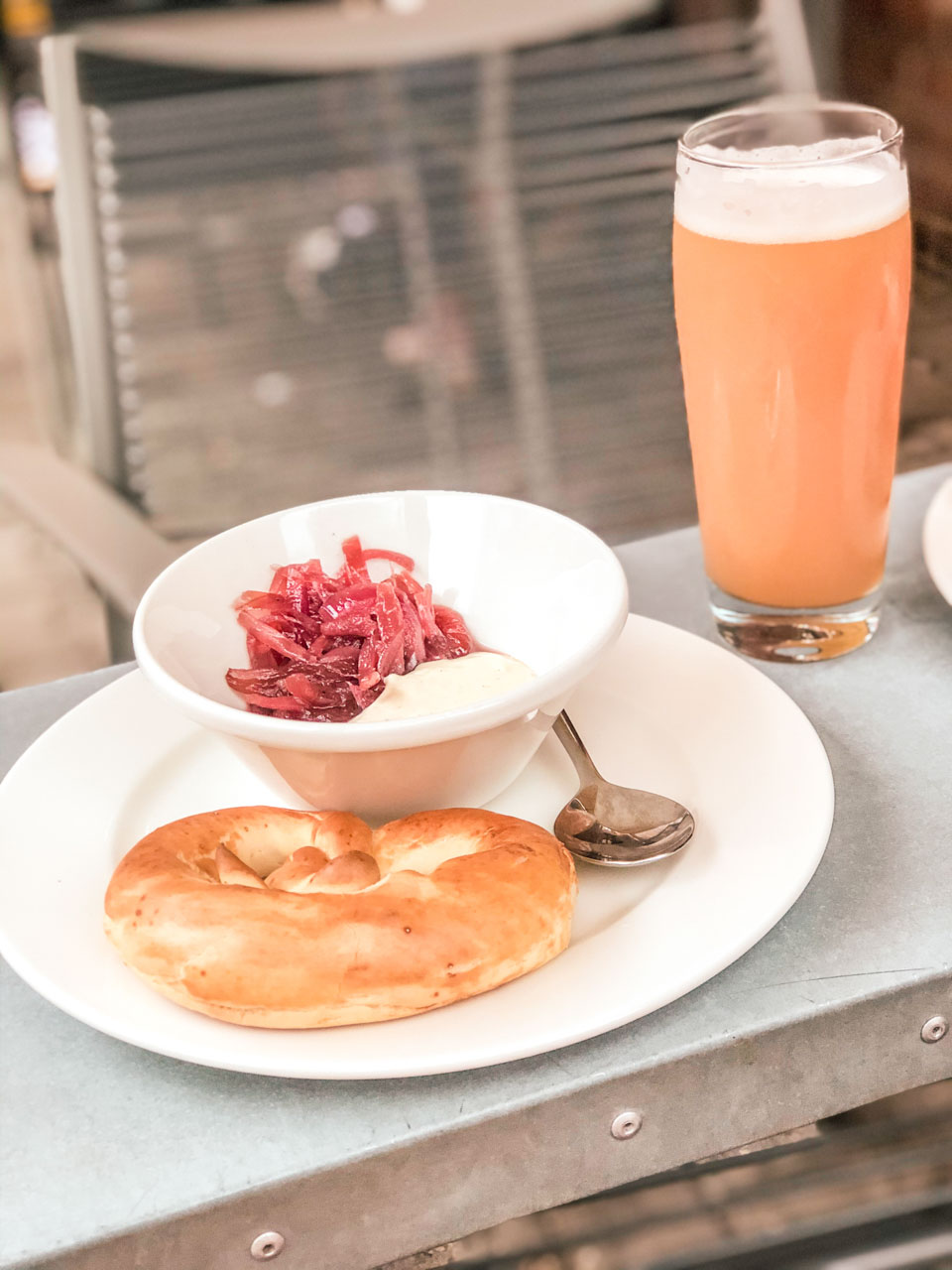 A beer pretzel with red onion jam and cheese sauce next to a glass of beer