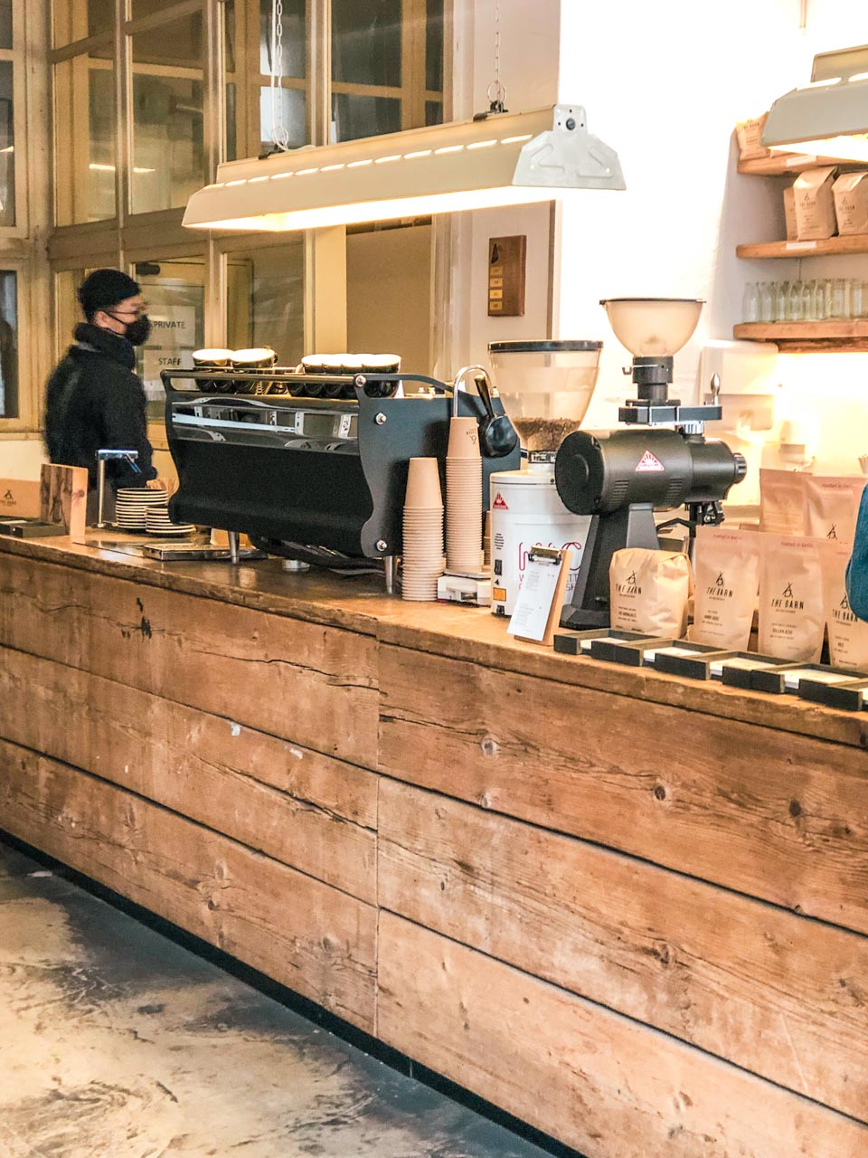 Espresso machine and coffee grinders on a wooden counter inside The Barn Coffee Roastery in Berlin