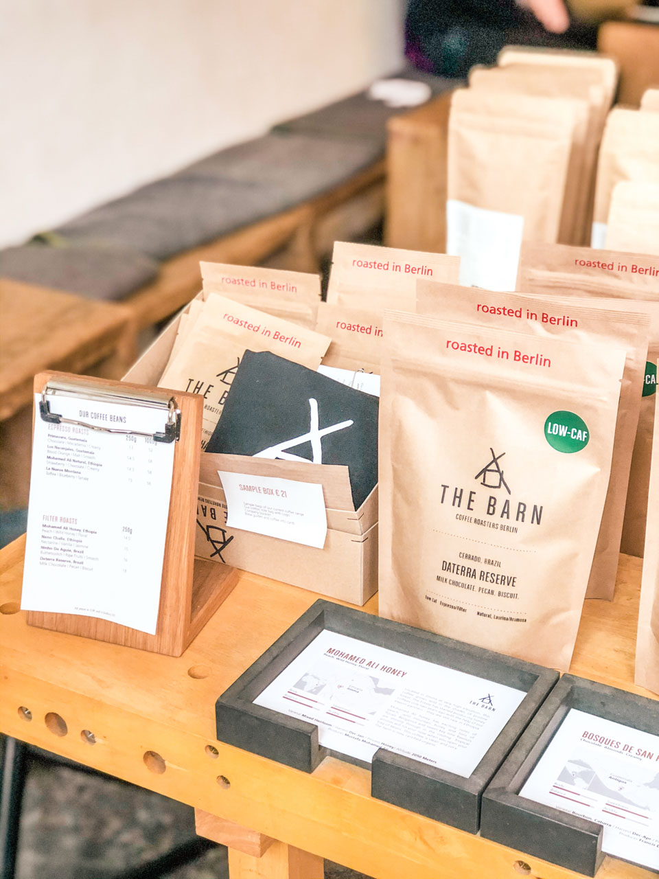 Sample bags of specialty coffee beans on a wooden table at The Barn Coffee Roastery in Berlin