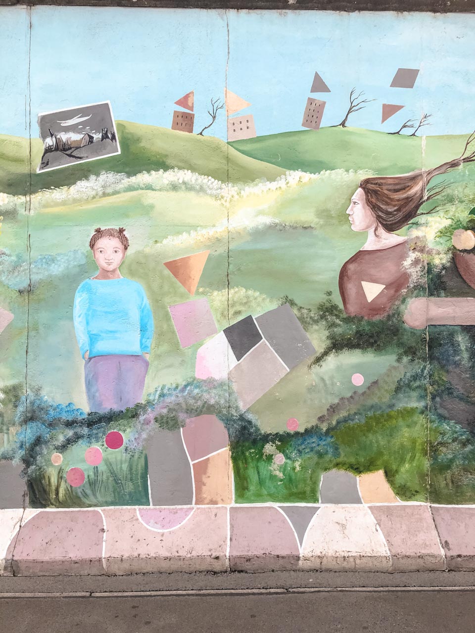 Mural at the East Side Gallery depicting a small girl and an adult woman standing on a meadow