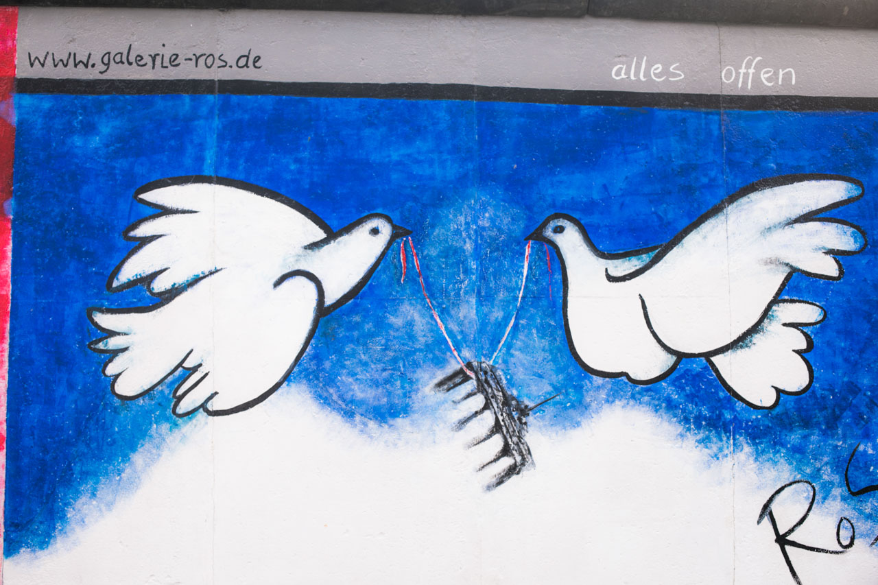 Mural depicting two white doves holding up the Brandenburg Gate at the East Side Gallery