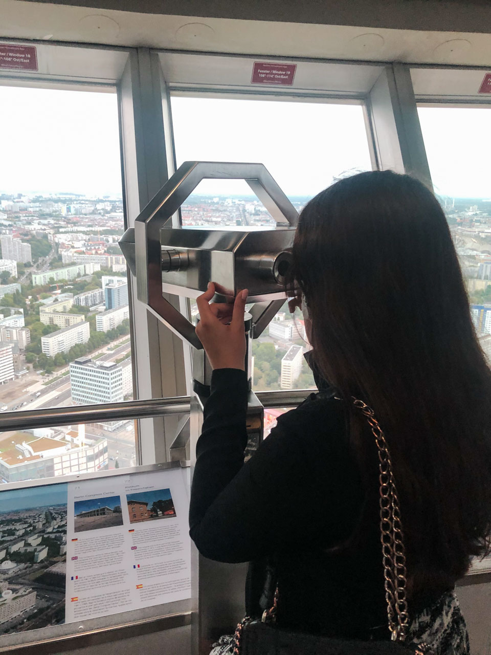 Woman looking through the binoculars on the observation deck of the Berlin TV Tower