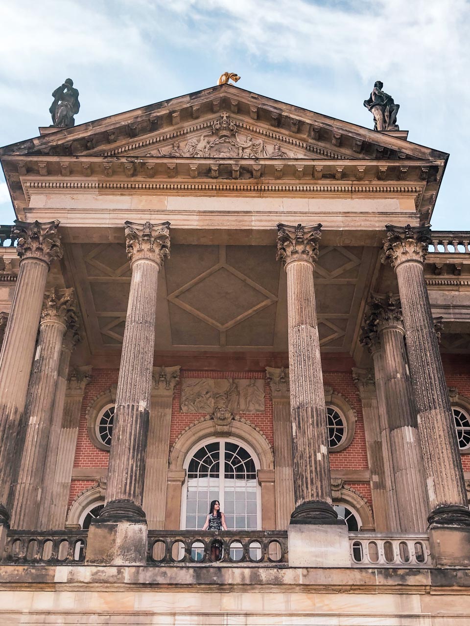 A woman leaning against a balustrade outside the University of Potsdam building at Sanssouci Park