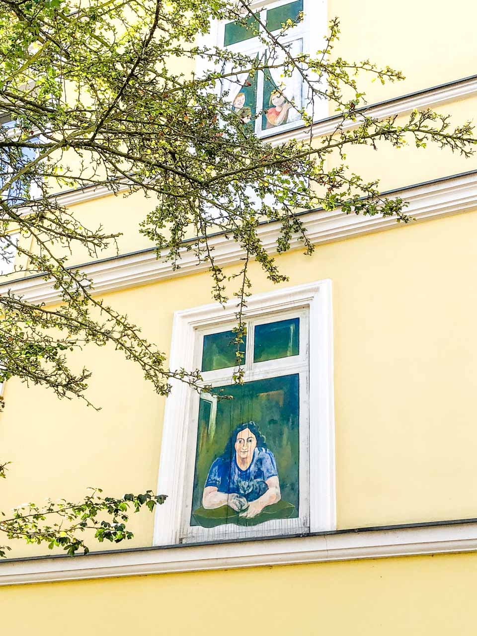 Mural on the wall of an apartment building in Potsdam showing a woman looking out of the window