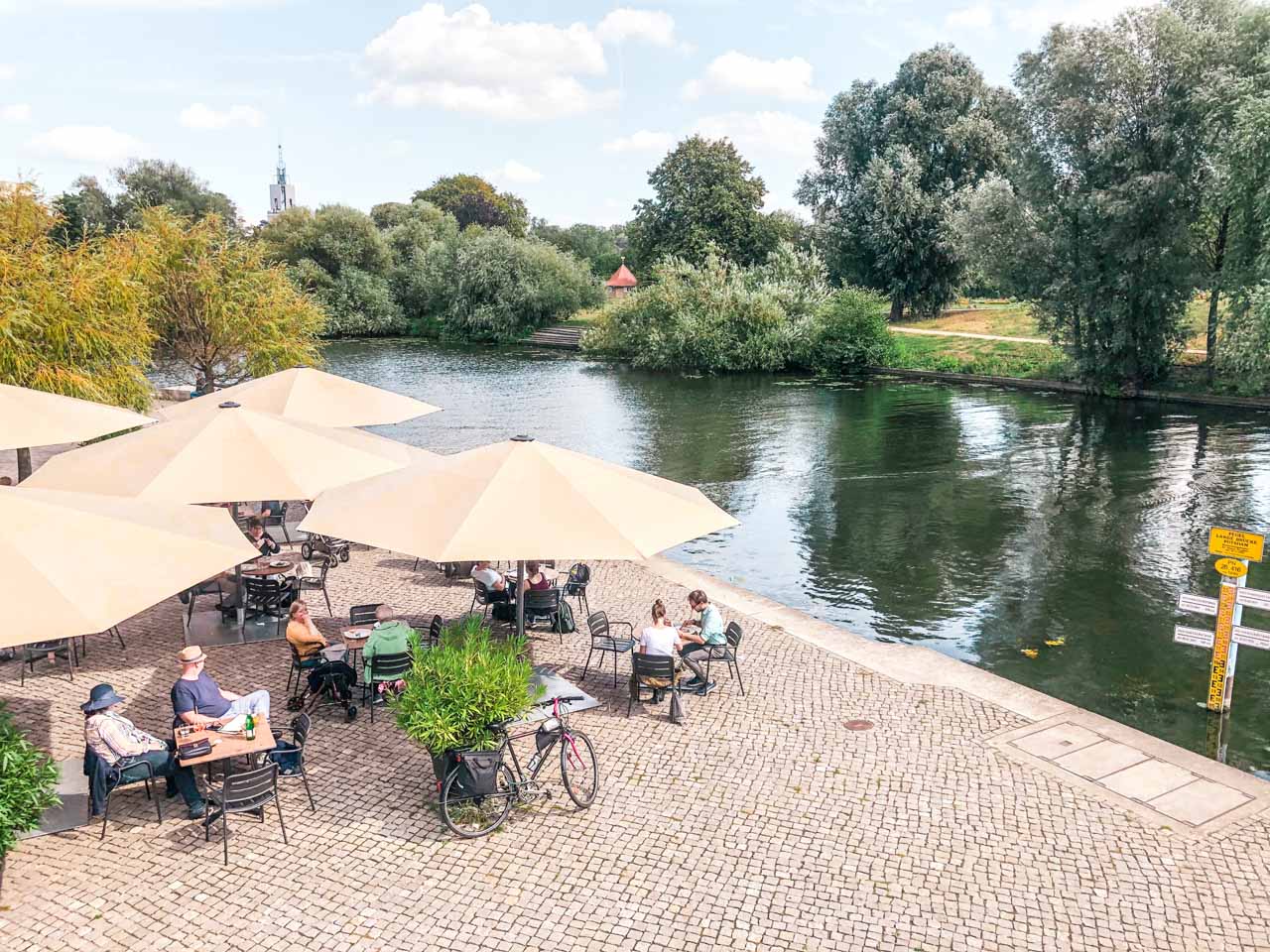 People sitting at tables by the Alte Fahrt in Potsdam, Germany