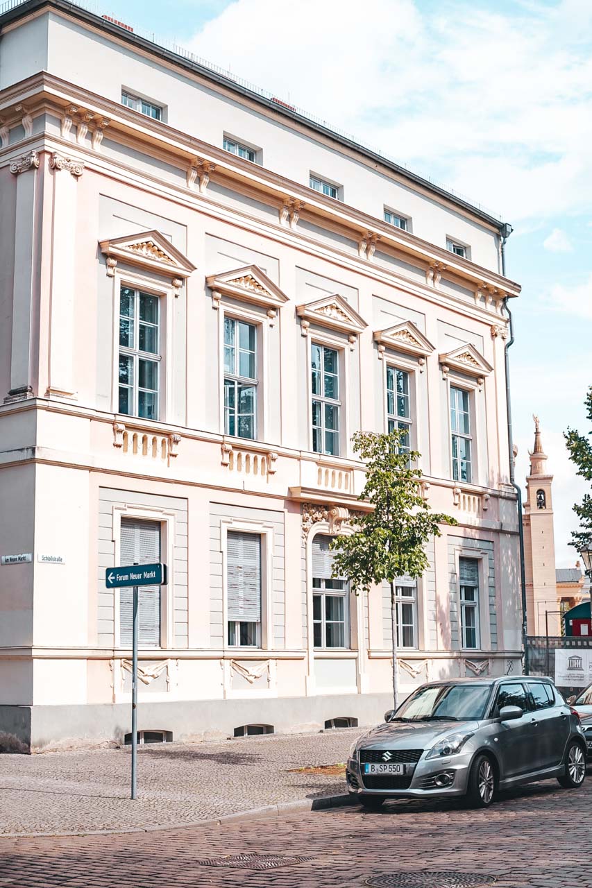 A car parked outside a pastel pink tenement house in Potsdam, Germany