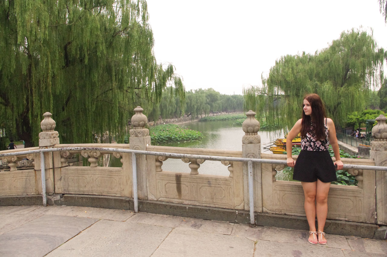 Woman in a playsuit looking sideways as she is standing on a bridge at Beihai Park in Beijing, China