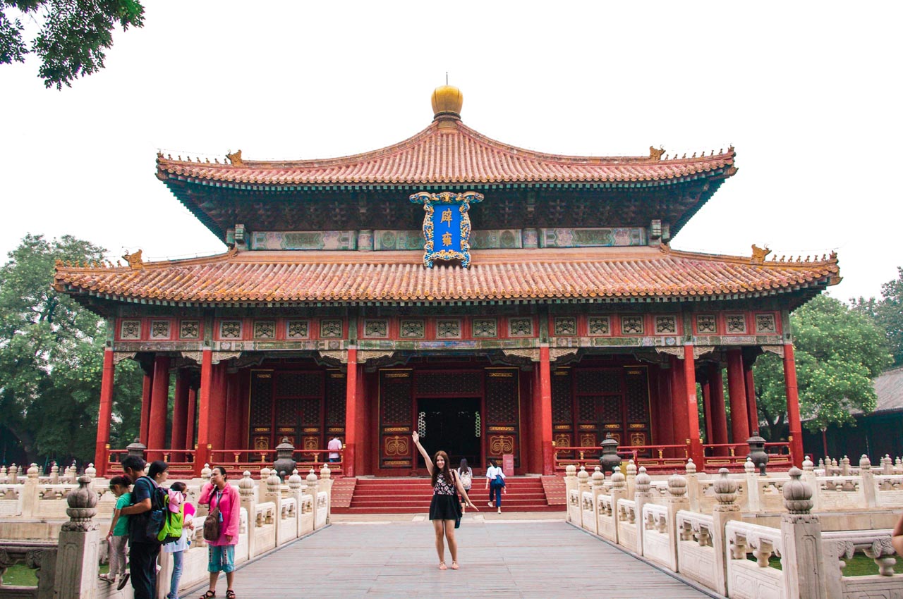 Woman throwing her hand up in the air on a bridge in front of the Temple of Confucius in Beijing