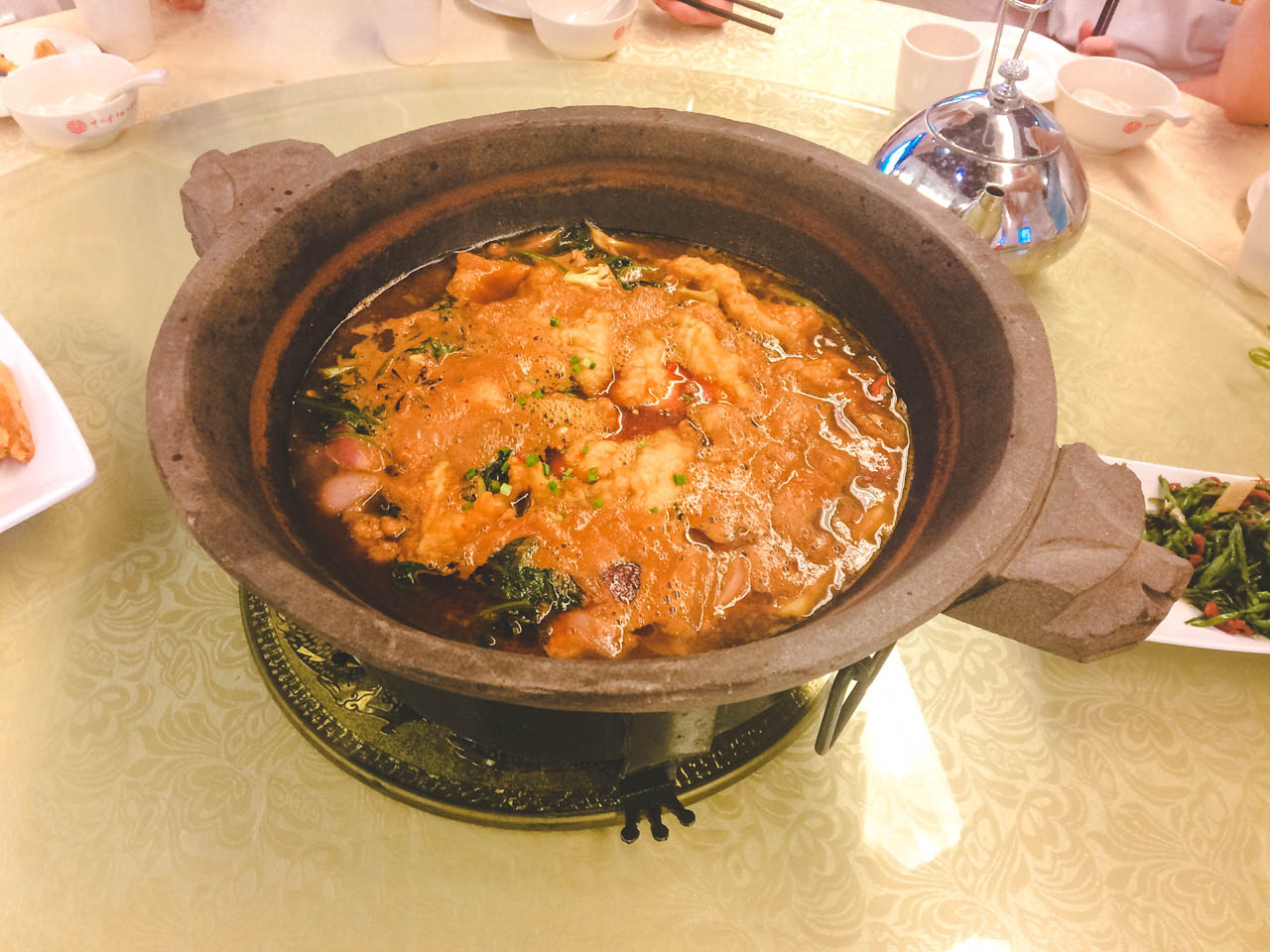 A Chinese dish inside a round clay dish on a Lazy Susan rotating table