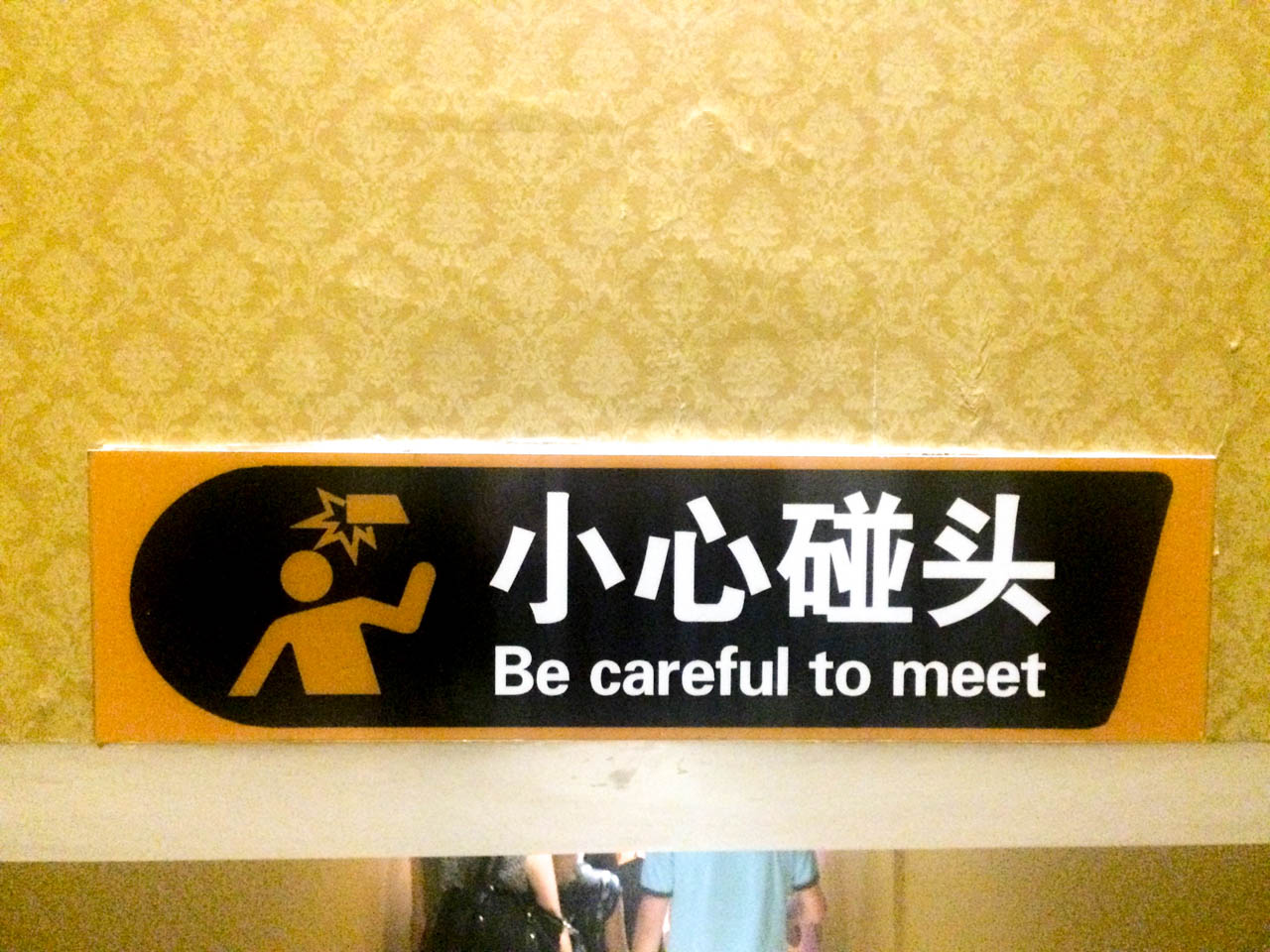 A wall sign with a funny Chinese translation that says "Be careful to meet"