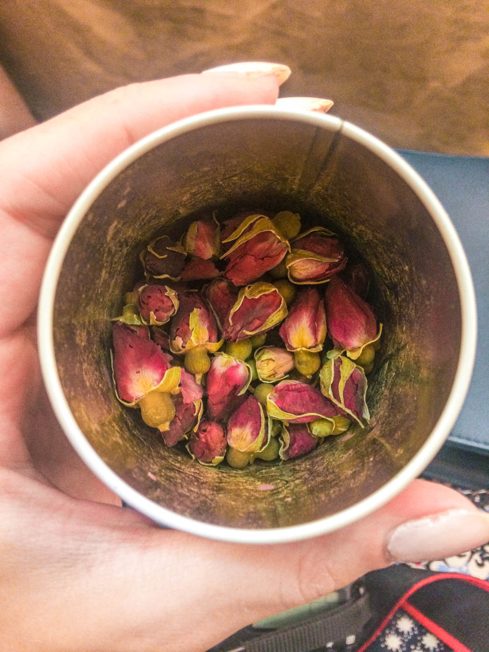 A close-up shot of a tea tin containing dried rose buds at a traditional tea shop in Beijing, China